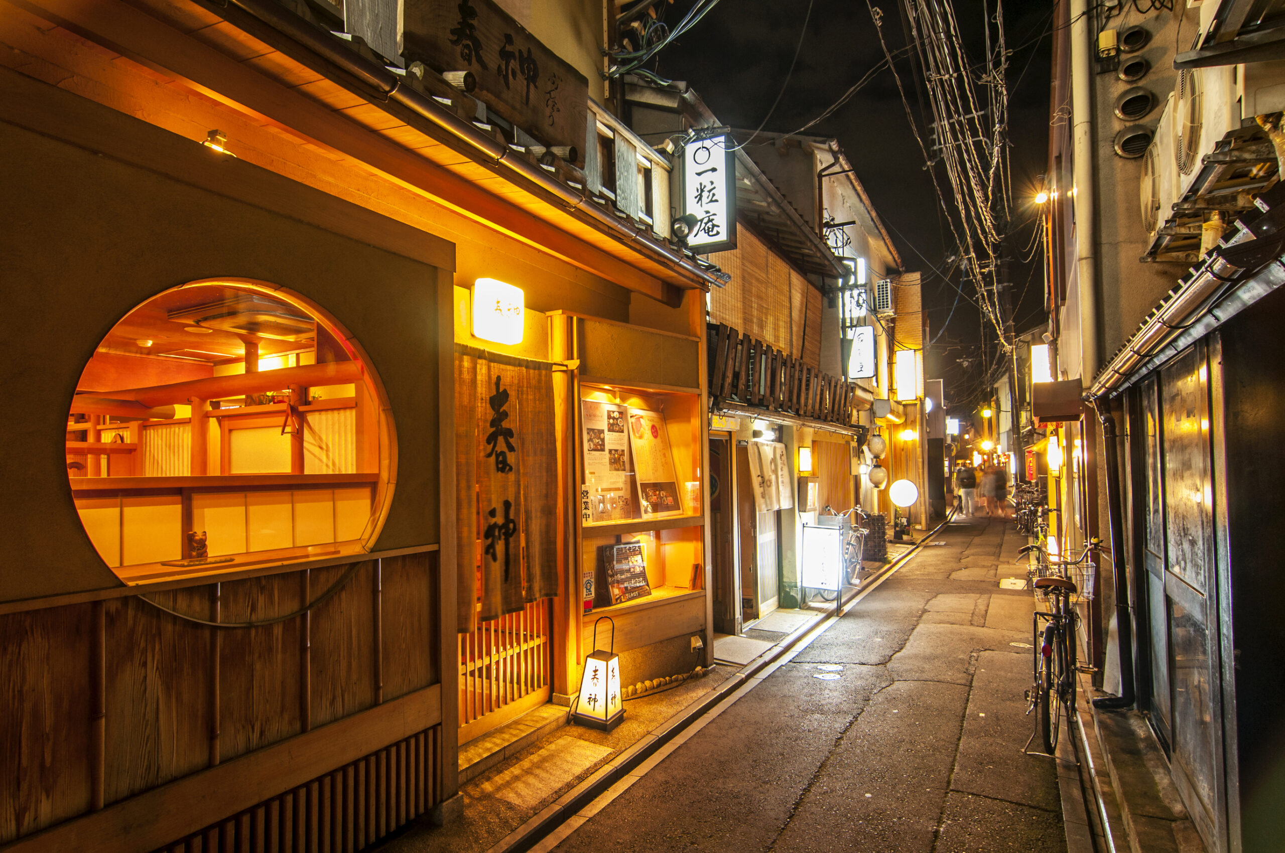 Pontocho Alley in Kyoto at night, lantern-lit with traditional wooden restaurants
