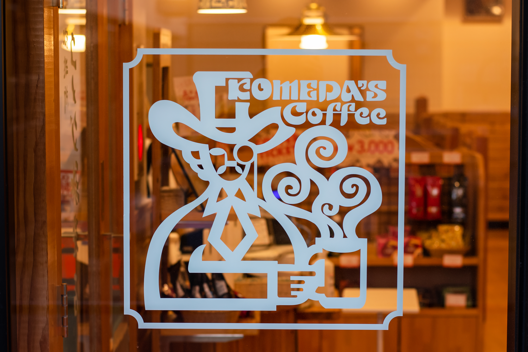 Komeda's Coffee logo etched on a store window in Japan