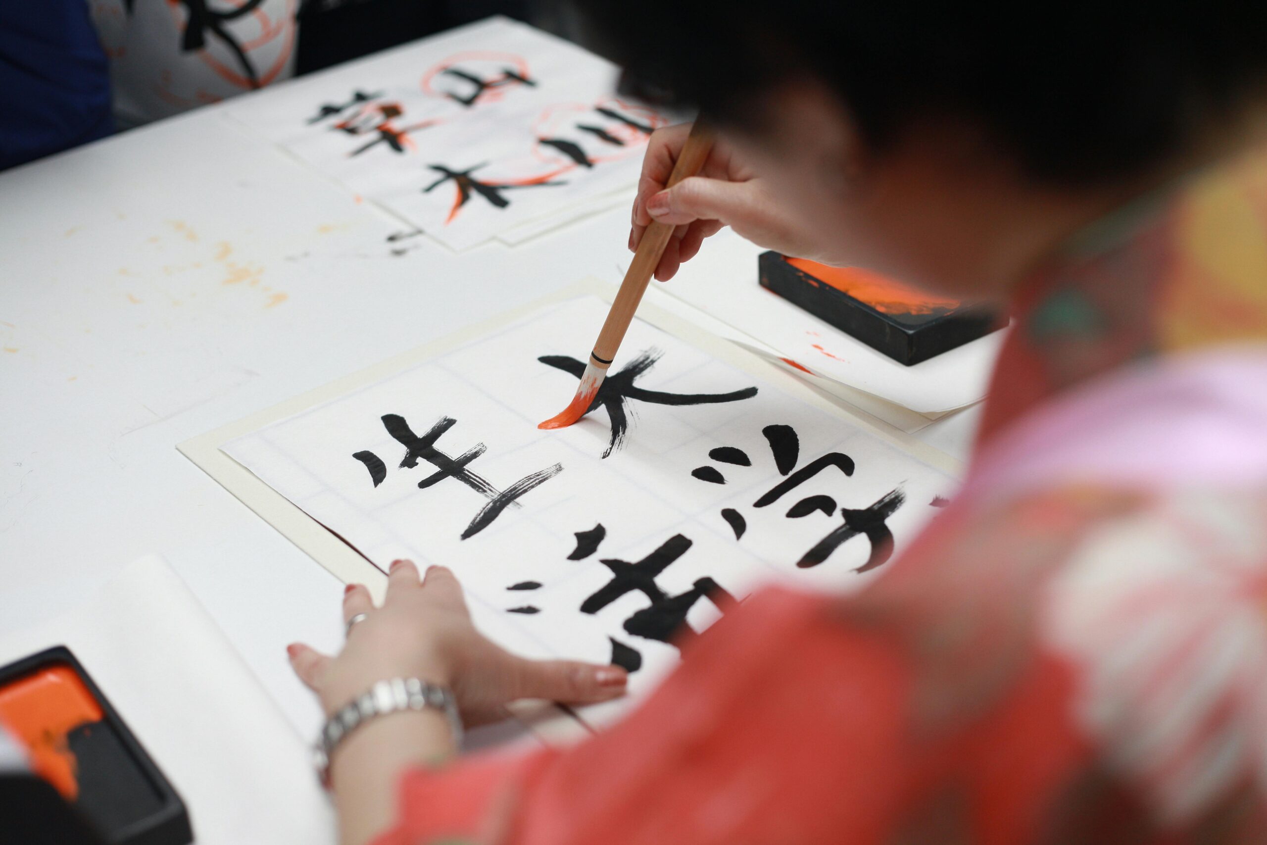 Writing the Japanese word daijoubu (大丈夫) in brush calligraphy, wearing a kimono