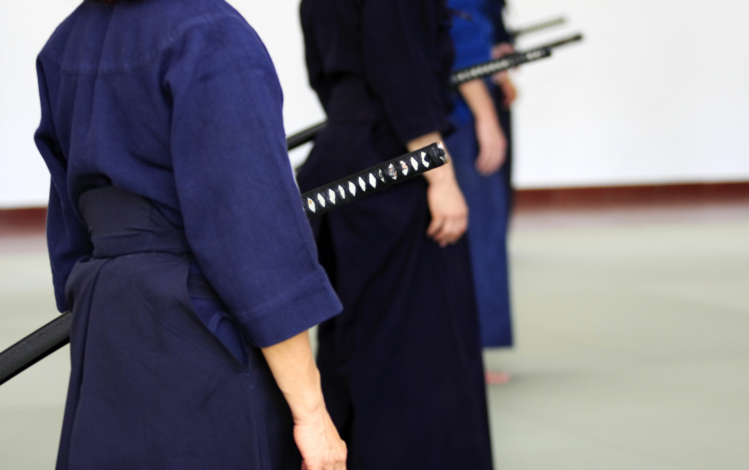 Practitioners in hakama holding Japanese swords, evoking samurai tradition