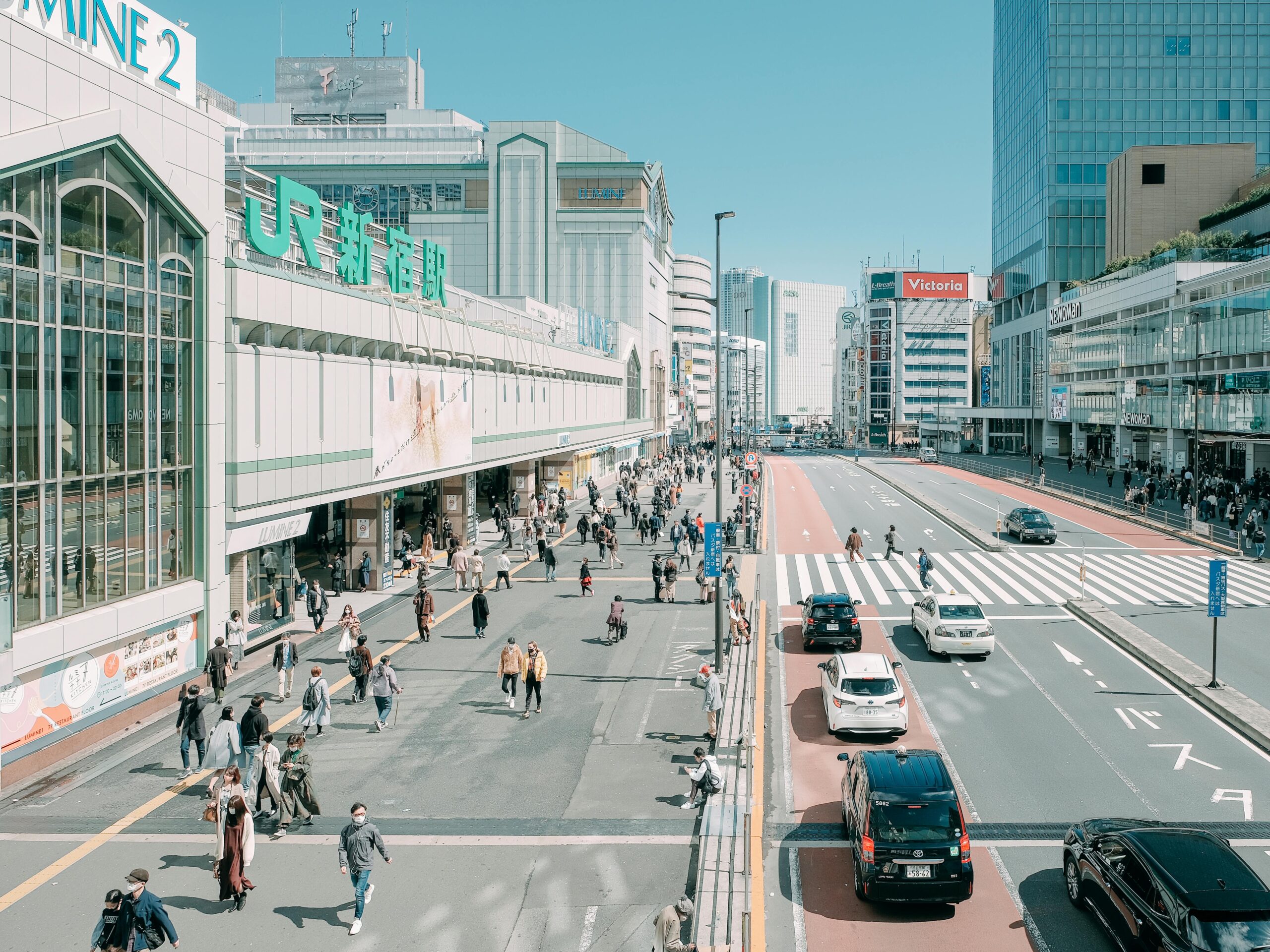 Busy street outside JR Shinjuku Station with cars driving on the left, Tokyo