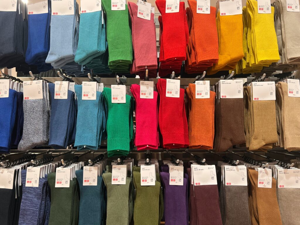 The genius of Uniqlo fashion: Capturing the universal appeal of Japanese minimalism 2 Colorful socks at a Uniqlo store, showcasing the brand's blend of Japanese minimalism and universal appeal in fashion.