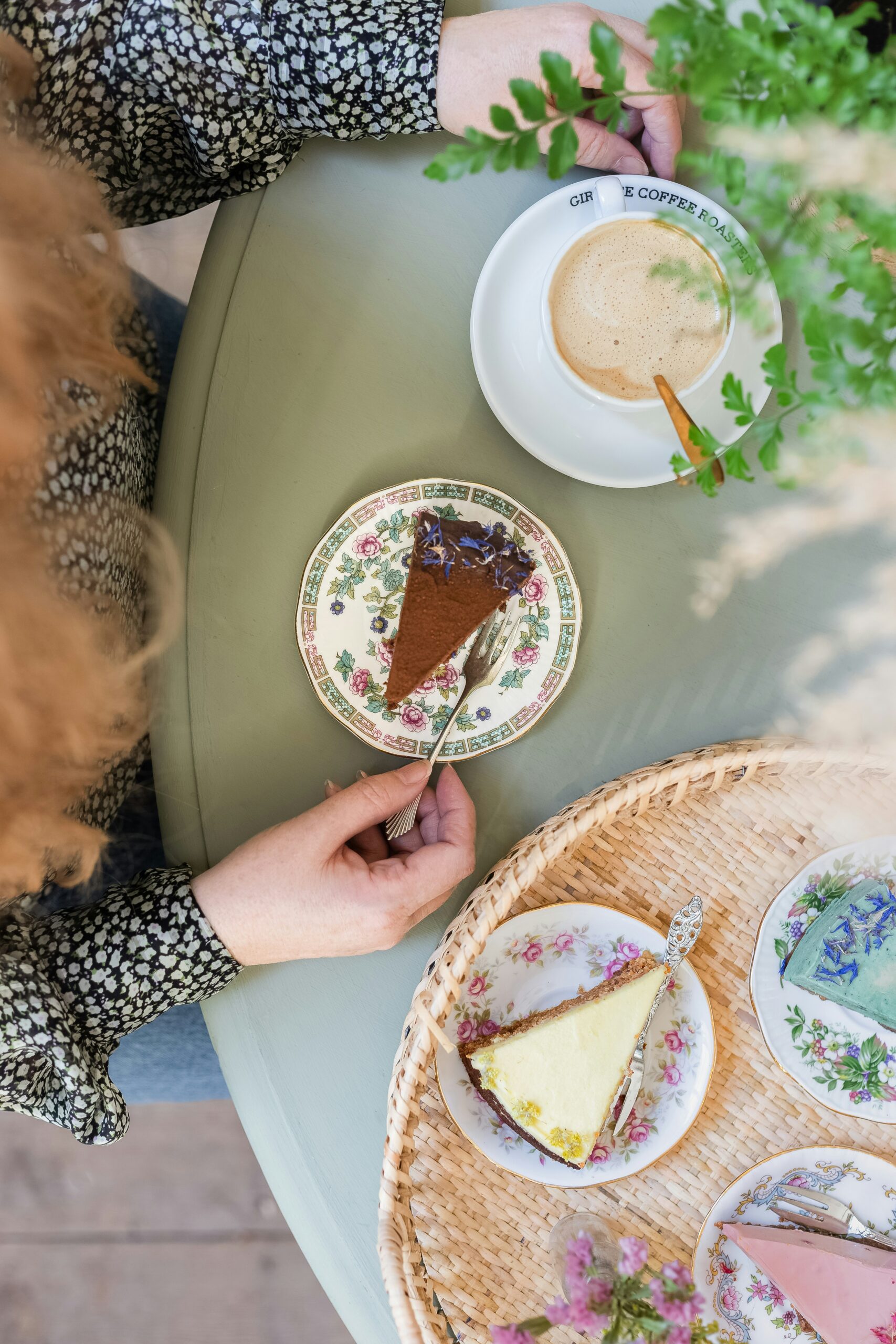 Top view of a woman enjoying coffee and a slice of cake.