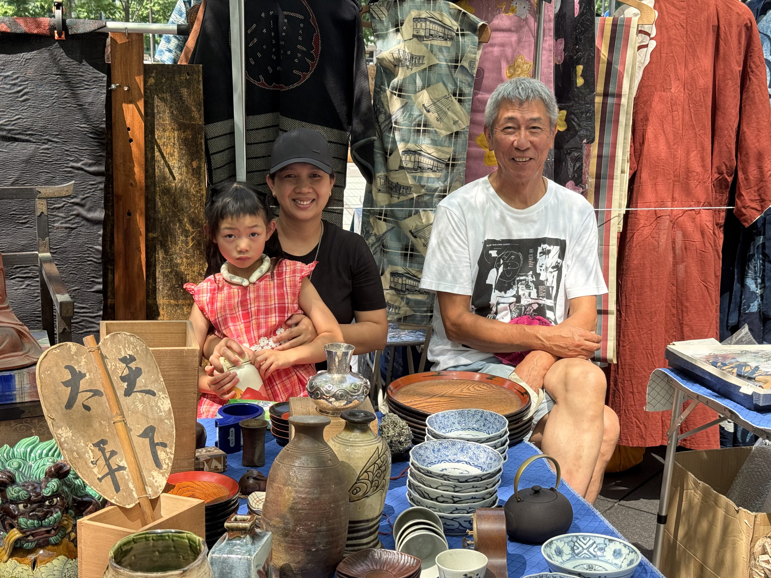 An antique stall at the Oedo Antique Market displaying ceramics, lacquer plates, and vintage textiles